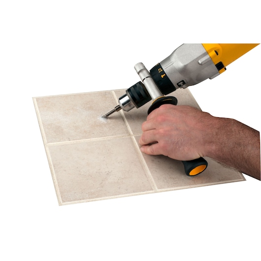 LENOX 121074DGDS tile drill bit in use with a power drill, making a hole in beige ceramic tile.
