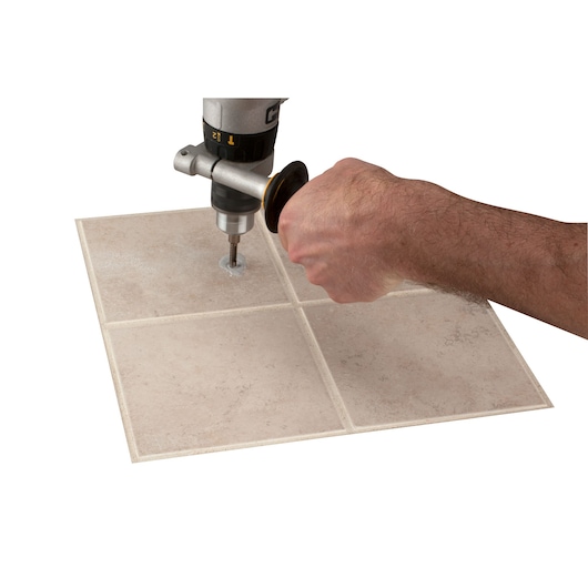 Photo of LENOX 1211110DGDS hole saw drilling through beige ceramic tile at a top-down angle.