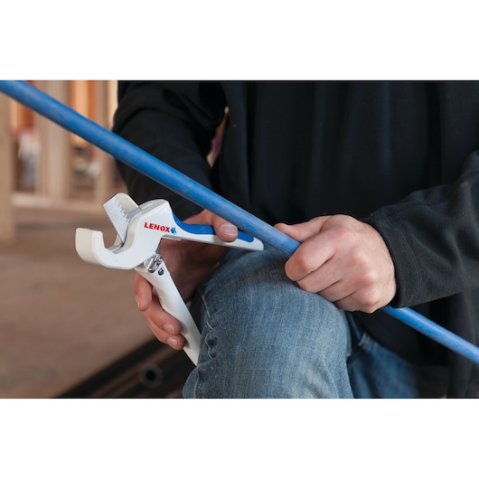 LENOX 12121S1 pipe cutter cutting a blue plastic pipe in a workshop setting.