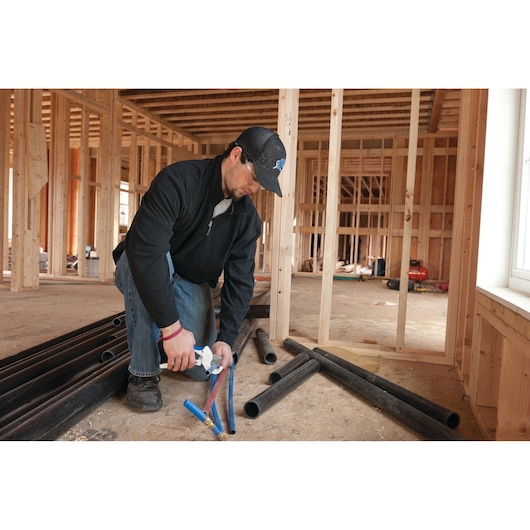 LENOX 12123R1 pipe cutter in use cutting plastic tubing at a construction site, product category photography.