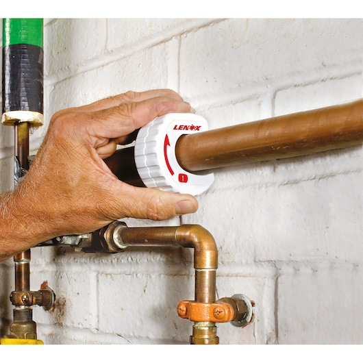 Photo of LENOX 14832TS1 tube cutter being used on a copper pipe against a white brick wall.