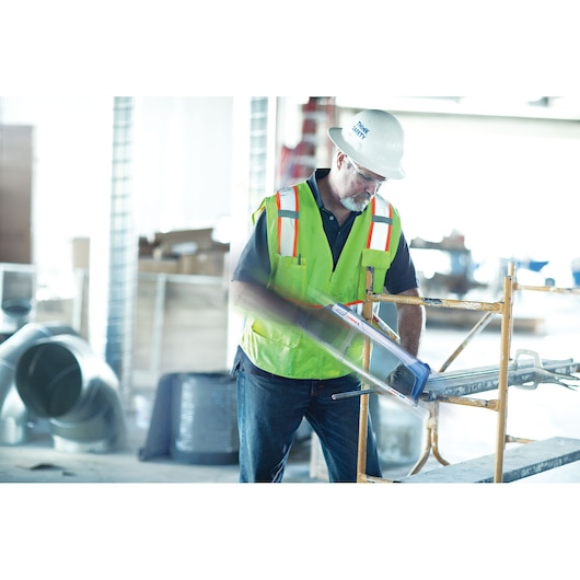 Photo of a worker in a yellow safety vest using a LENOX 1884466 hand saw to cut metal pipe on a construction site.