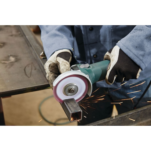 LENOX 1972921 metal grinding wheel in use, mounted on angle grinder, producing sparks while cutting steel tube.