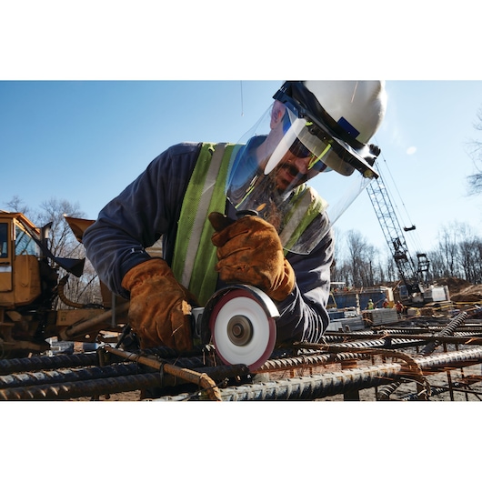 LENOX cutting wheel 1972921 in use on rebar at construction site, worker wearing gloves, safety vest, and face shield.