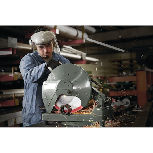LENOX 1972932 metal cutting saw in use, operator wearing safety gear, cutting metal pipe with sparks flying, workshop background.