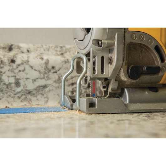 Close-up photo of LENOX jigsaw blade 1991387 mounted on a jigsaw cutting through a stone countertop.