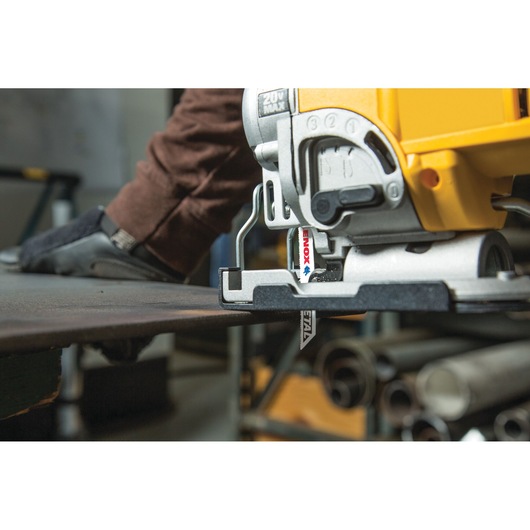 Photo of LENOX 1991595 jigsaw blade mounted in a jigsaw cutting metal sheet in a workshop.