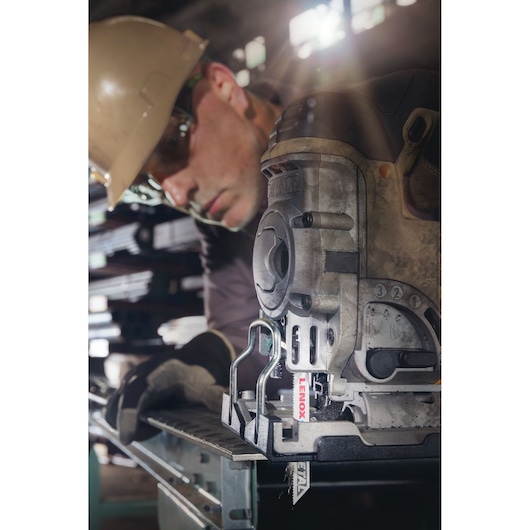Photo of LENOX jigsaw blade SKU 1991599 cutting metal, mounted in a powered jigsaw in an industrial setting.