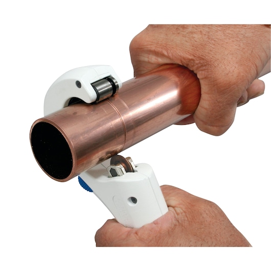 LENOX 21008TC58 pipe cutter tool cutting copper pipe, close-up hand operation, white background.