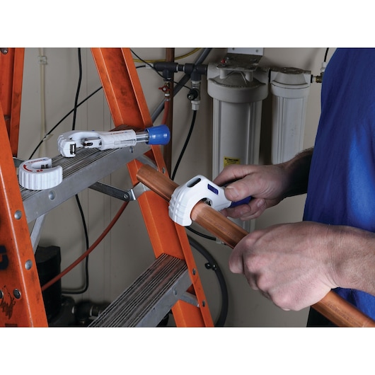 LENOX 21008TC58 pipe cutter in use on copper pipe near an orange ladder, plumbing tools and equipment visible.