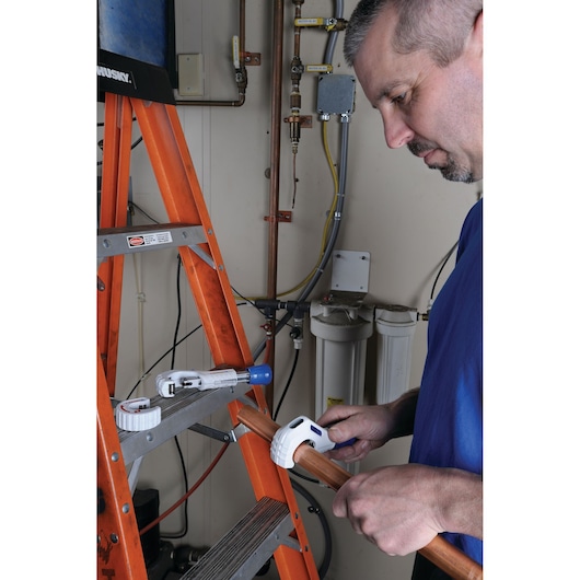 LENOX 21008TC58 pipe cutter in use cutting copper pipe near an orange ladder in a utility room.