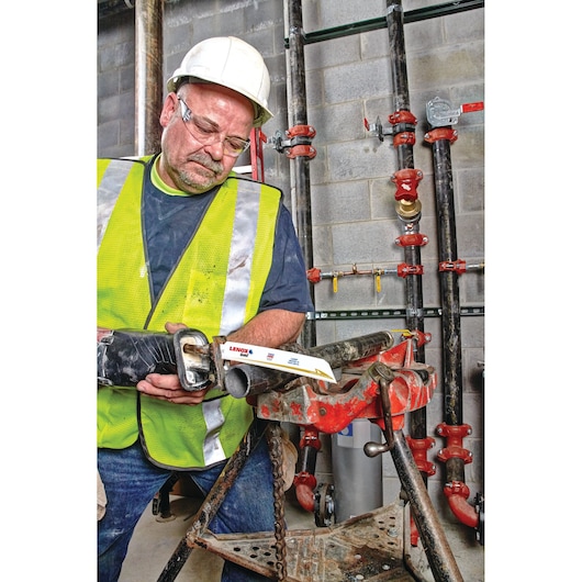 LENOX 210989114GR reciprocating saw blade cutting metal pipe on construction site, worker in safety gear.