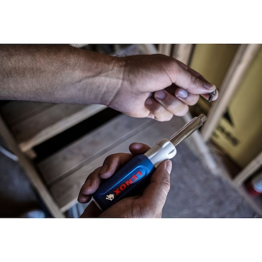 Photo of LENOX 23931_ blue-handled screwdriver with bit, held in hand during assembly.