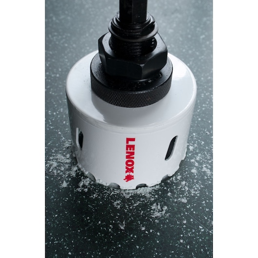 LENOX 2996666CG hole saw with black arbor, white body, cutting through dark speckled surface.
