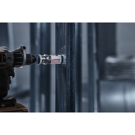 Photo of LENOX hole saw 3002222L attached to a power drill cutting through metal framing.