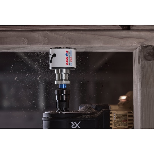LENOX 3004141l hole saw cutting through wood attached to a power drill, with wood dust in the air.