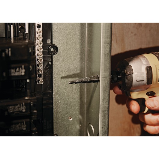 Photo of LENOX step drill bit SKU 30884VB4 attached to a power drill in use on a metal electrical panel.