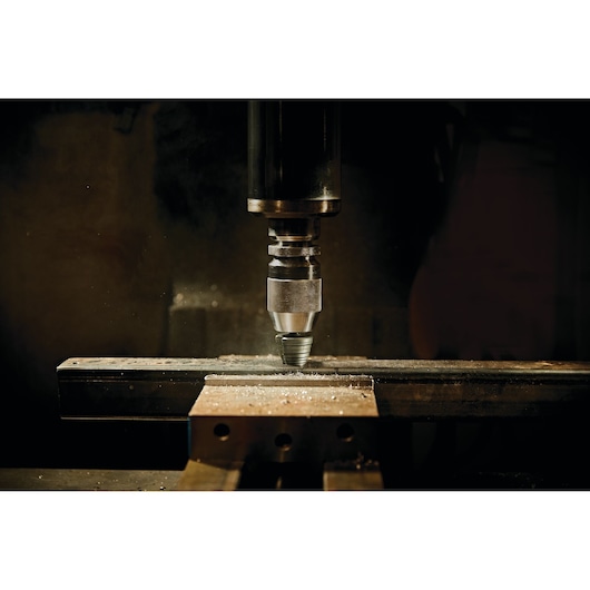 LENOX 30912VB12 step drill bit cutting through metal bar, close-up photography with dark background.