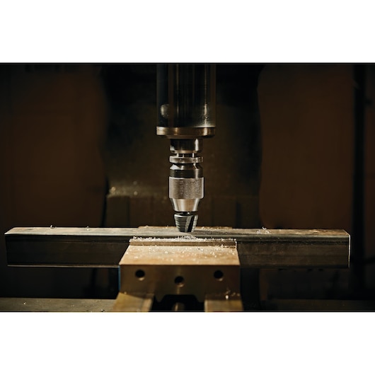 LENOX 30912VB12 drill bit in a drill press cutting through metal bar, close-up photography.