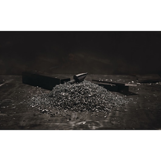 Photo of LENOX 30912VB12 step drill bit on metal surface with pile of metal shavings.