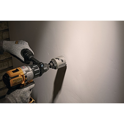 LENOX LXAH3218 hole saw attached to drill cutting into drywall, close-up photo of product in use.