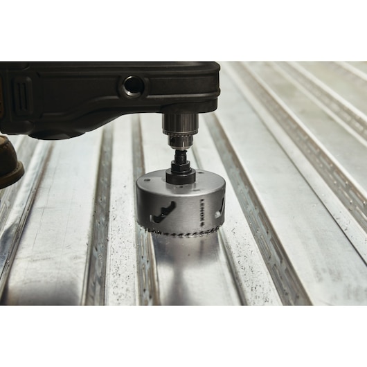 LENOX hole saw LXAH3412 attached to a drill cutting through metal surface, close-up photography.