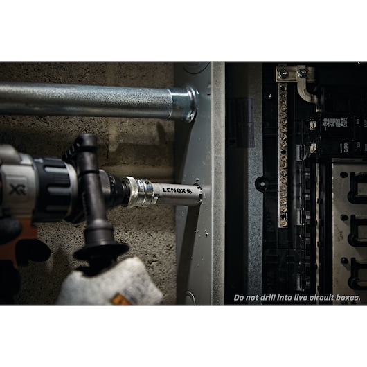 LENOX LXAH378 hole saw attached to drill cutting into metal electrical box near circuit panel.