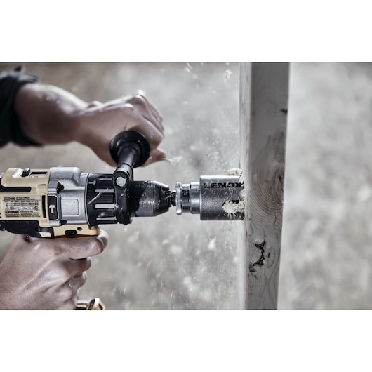 LENOX hole saw LXAH4218 attached to a power drill cutting through a wooden board, close-up action shot.