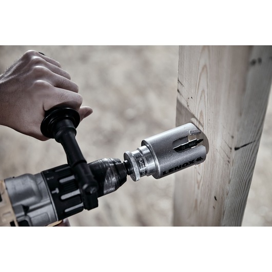 LENOX LXAH4218 hole saw attached to drill making a round cut in wooden beam, close-up photography.