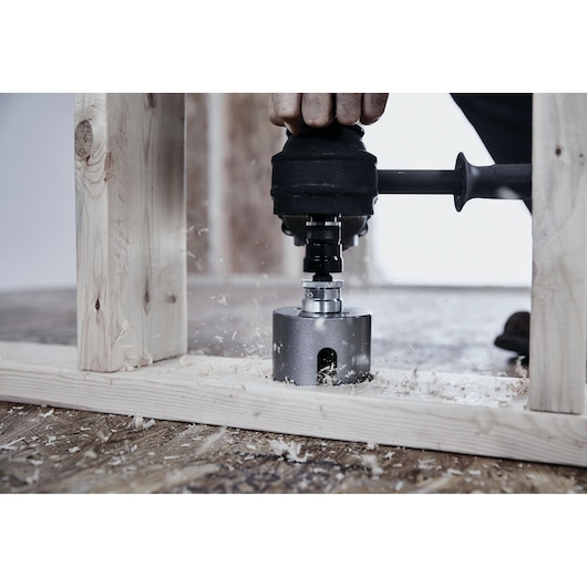 LENOX LXAH4358 hole saw drilling through wood frame with power drill, wood shavings scattered.
