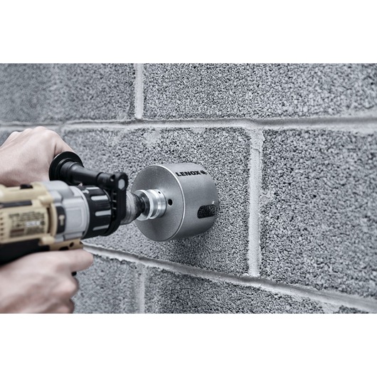 LENOX LXAH44 hole saw drilling into concrete block wall, close-up of tool in use.