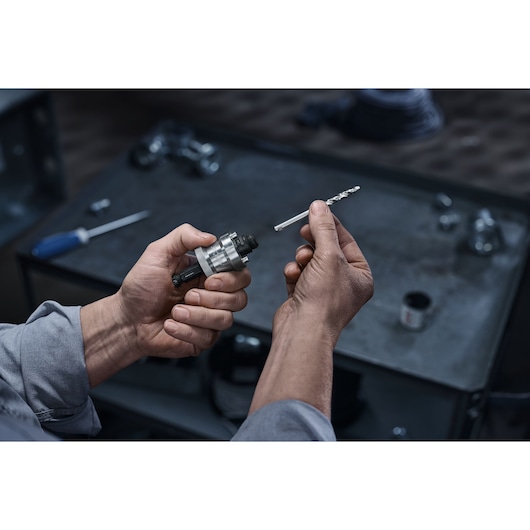 LENOX LXAH9912PBM hole saw arbor being held with a pilot drill bit in a workshop setting.