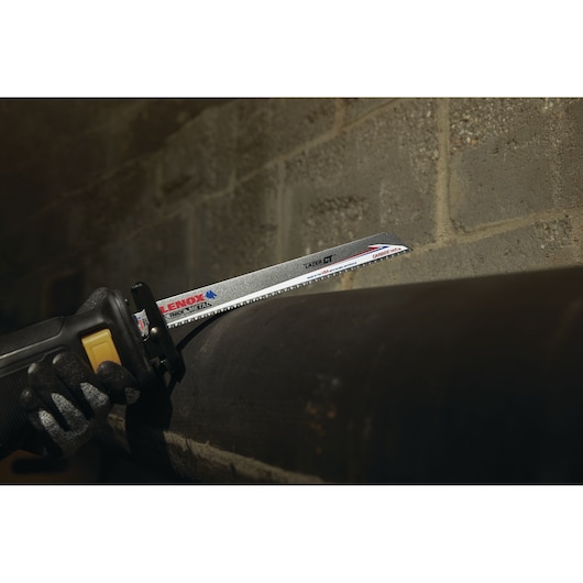 Photo of LENOX reciprocating saw blade LXAR12108CT cutting through thick metal pipe, side view.