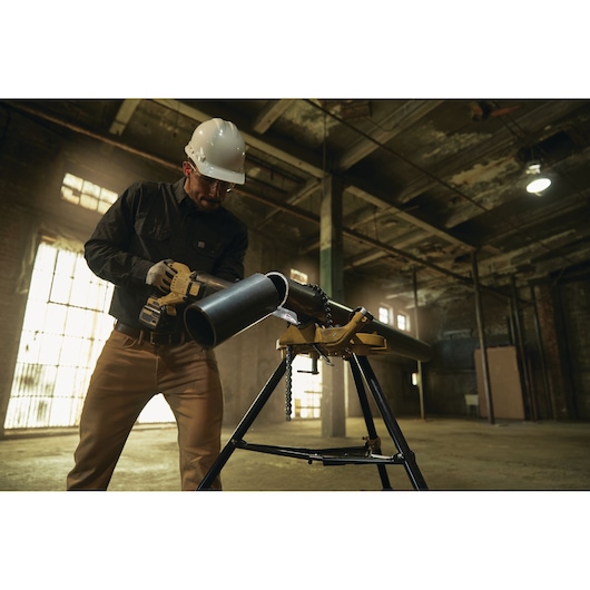 LENOX LXAR9110CT-1 reciprocating saw cutting a metal pipe held in a tripod vise in an industrial setting.