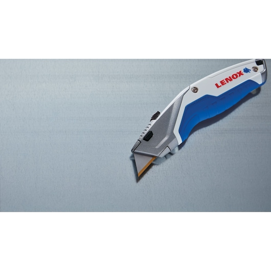 Photo of LENOX utility knife LXHT10599, silver and blue handle, angled on a gray surface.