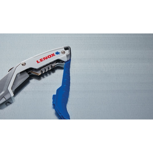 Photo of LENOX utility knife with blue grip, partial side view, SKU LXHT10599, on metallic background.