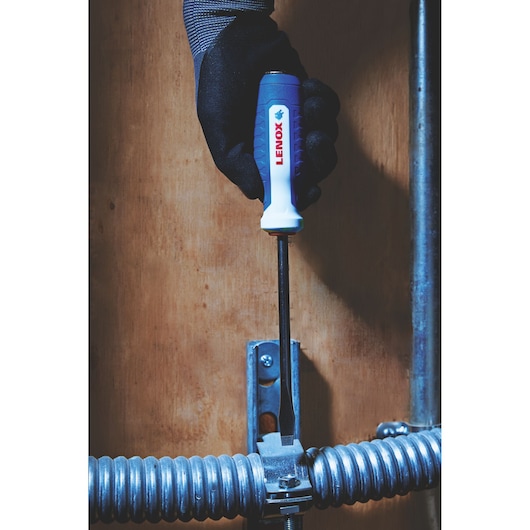 Photo of LENOX LXHT60900 screwdriver in use by a gloved hand tightening a metal fixture.