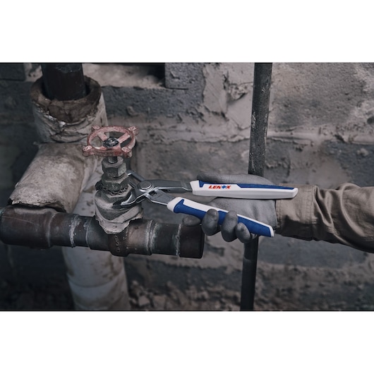 Photo of LENOX LXHT90552 groove joint pliers with blue and white handles being used to grip a pipe valve.