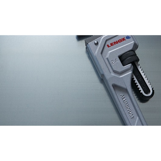 Photo of LENOX LXHT90624 aluminum pipe wrench, silver with black adjustment, angled on metallic surface.
