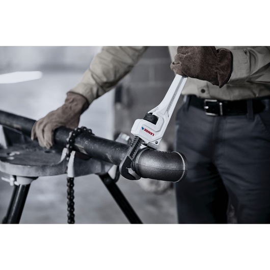 LENOX LXHT90714 pipe wrench in use gripping metal pipe by worker wearing gloves.