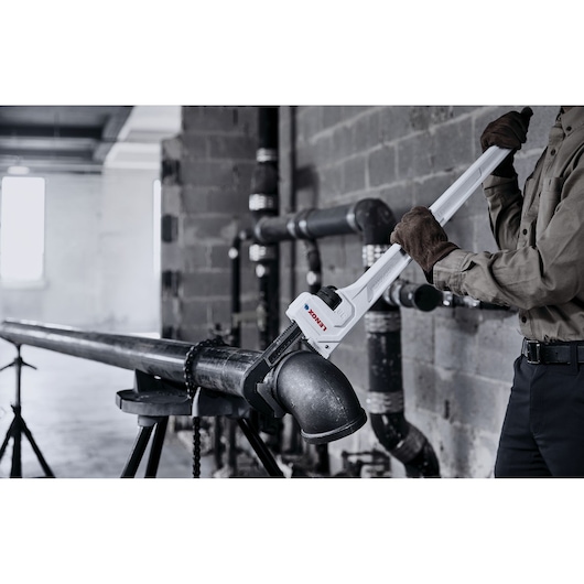 LENOX LXHT90736 pipe wrench being used to tighten a large metal pipe elbow in an industrial setting.